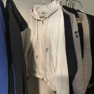 Vit moncler zip up hoodie  - Säljer en snygg vit zip hoodie från Moncler. Passar till alla tillfällen när du vill vara både bekväm och stilren. Skicket är som nytt, tröjan är äkta och kostar ny runt 4500kr, mitt pris kan diskuteras vid snabb affär. Byten kan även va intressant.