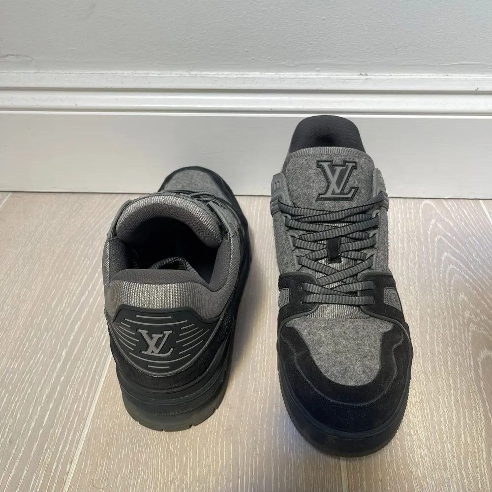 Säljer ett par snygga Louis Vuitton sneakers i grått och svart. De har en stilren design med LV-loggan på plösen och hälen. Skorna är i mycket bra skick och har en bekväm passform. Perfekta för både vardag och fest!. Skor.