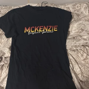 Svart t-shirt från McKenzie - Säljer en svart t-shirt från McKenzie med färgglatt tryck på bröstet. Perfekt för en avslappnad stil och passar till både jeans och shorts. T-shirten har en normal passform och är kortärmad. Skön och enkel att matcha med andra plagg!
