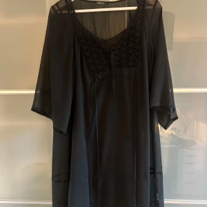 Svart klänning med spetsdetaljer - Själva klänningen är genomskinlig och därför finns det en underklänning till. Den har spets och knyt detaljer vid bysten. Det finns ingen lapp kvar så vet tyvärr inte vilken märke eller storlek det är, men skulle gissa på M