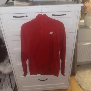Röd hoodie från Nike - Säljer en snygg röd hoodie från Nike med dragkedja och klassisk logga på bröstet. Perfekt för en avslappnad stil.