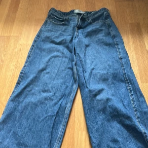 Blå Holister Low rise baggy jeans - Säljer ett par klassiska blå jeansbyxor med en loose passform. Byxorna har en låg midja och raka ben, vilket ger en avslappnad stil. Perfekta för en casual look.