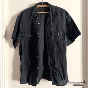 Svart skjorta - Kortärmad skjorta i storlek M. Plagget är thriftad, så vet ej vilket material eller märke det är. Har använts fåtal gånger, men väldigt fint skick! Alla använda plagg tvättas noga innan leverans! Det är bara att skriva om du har några frågor! <3 