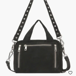 Svart axelväska från Núnoo - Snygg svart axelväska från Núnoo i mocka med coola dragkedjedetaljer. Väskan har två justerbara axelrem, en med nitar och två praktiska handtag. Modell Donna.