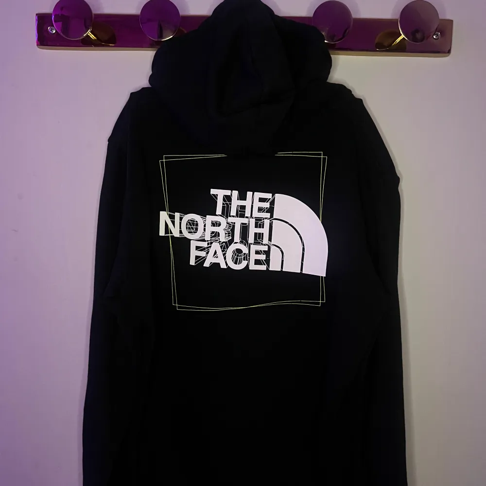 Säljer en svart hoodie från The North Face med logga både fram och bak. Hoodien har en klassisk design med dragsko i huvan och en stor ficka framtill. Perfekt för en avslappnad stil.. Neuletakit & Villapaidat.
