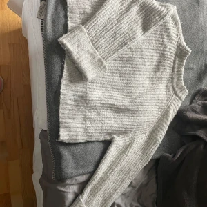 Grå stickad tröja från Gina Tricot - Mysig grå stickad tröja från Gina Tricot i storlek XL. Tröjan har en ribbad design med långa ärmar och en bekväm passform. Perfekt för kyliga dagar.