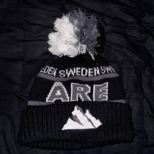 Svart åre mössa  - Snygg svart mössa med grå och vit text. Jättesnygg men kommer inte till användning. Helt ny och aldrig använd🤩