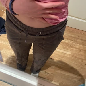 Grå mjukisbyxor med snörning - Säljer ett par bekväma grå mjukisbyxor i storlek XS. Byxorna har en elastisk midja med snörning och praktiska fickor framtill. Perfekta för en avslappnad stil.