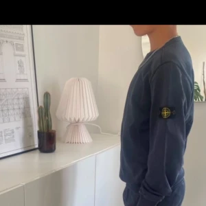 Mörkblå tröja från Stone Island - Säljer en andvänd mörkblå tröja från Stone Island med deras ikoniska märke på ärmen. Tröjan har långa ärmar och en rund halsringning. Perfekt för en avslappnad look.