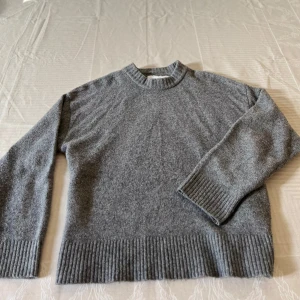 Grå stickad tröja  - Säljer en stilren grå stickad tröja från Junkyard i storlek S men passar även M. Tröjan har långa ärmar och ribbstickade muddar vid ärmslut och nederkant. Perfekt för kyliga dagar. Hör av dig vid intresse!