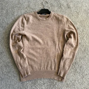 Beige merinoull J.Lindeberg - Säljer en stilren beige tröja från J.Lindeberg i mjuk merinoull. Tröjan har en klassisk rund hals och långa ärmar med ribbade muddar. Perfekt för kyligare dagar och enkel att matcha med olika outfits. Strl S men rekommenderar för XS!