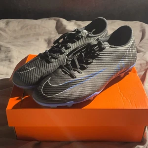 Svarta Nike Mercurial fotbollsskor - Säljer ett par svarta nike mercurials storlek 42(26,5 cm)som endast använts ett fåtal gånger, dock är dem lite creasade i fram. Säljer dem eftersom jag växte ur dem snabbt. Nypris 699kr 
