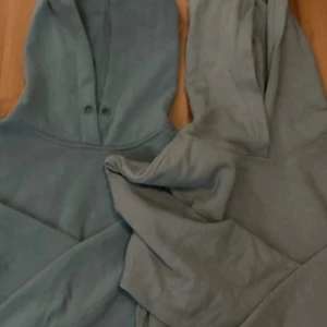 Grå hoodie med knappar - Säljer en stilren grå hoodie med knappar vid halsen. Perfekt för en avslappnad look. Den har en klassisk design med huva och är tillverkad i ett mjukt material.