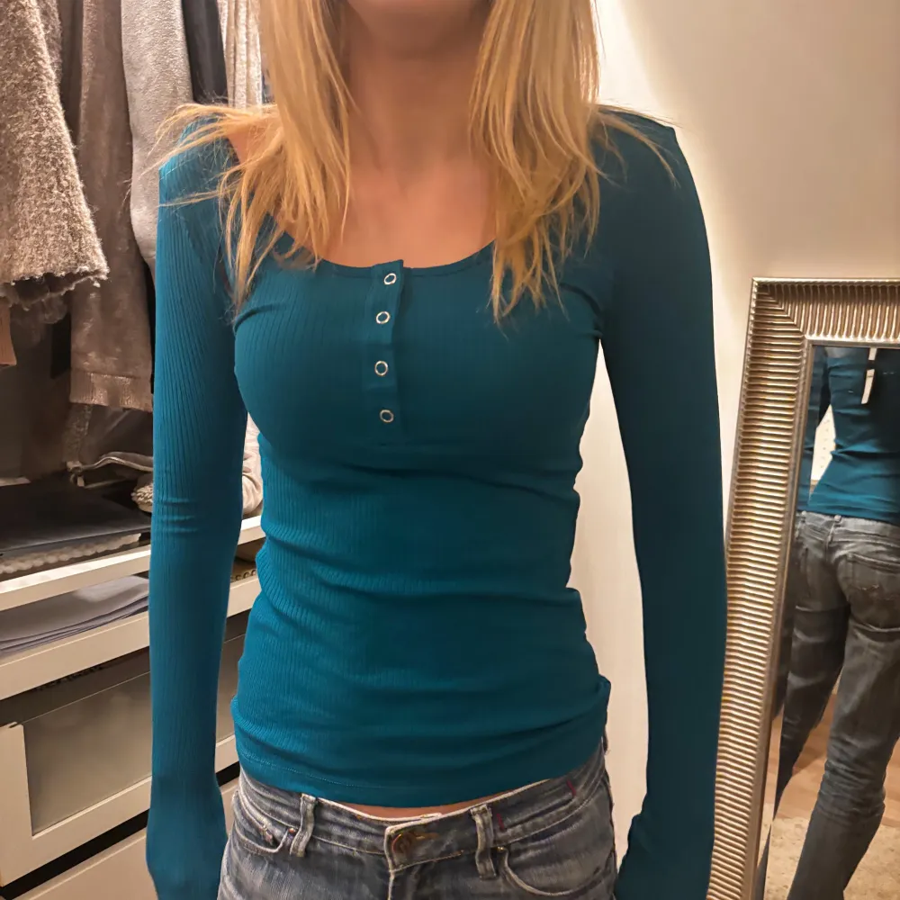 Snygg blå ribbad topp med långa ärmar och knappar framtill. Perfekt för en stilren look. Prislappen är kvar! . Neuletakit & Villapaidat.