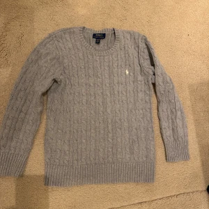 Ralph Lauren kabelstickad tröja  - Fin grå kabelstickad tröja som använts ett fåtal gånger. Den ser ut som ny. Strl 14-16 år, något liten i storleken så skulle säga att den motsvarar 158/164cl. 