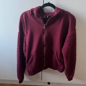 Vinröd hoodie från Bershka - Säljer en vinröd hoodie från Bershka då den inte riktigt var min stil. Ärmarna har en unik textur som ger en cool look. Perfekt för kyliga dagar och avslappnade stunder. 🧥🫶