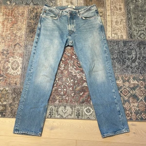 Ljusblå jeans från Jack & Jones - Snygga blå jeans från Jack & Jones med en klassisk straight fit. De har en ljus tvätt och är perfekta för en avslappnad stil. Jeansen har fem fickor och en knappgylf. Märkeslappen i läder sitter på baksidan av midjan.