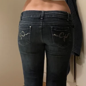 Mörkblå jeans med strassdetaljer - Snygga mörkblå jeans med strassdetaljer på bakfickorna. De har en klassisk femficksdesign och en bootcut-stil som ger en tidlös, midja:37cm Innerbenslängden:78cm tveka inte om du har en fråga❤️