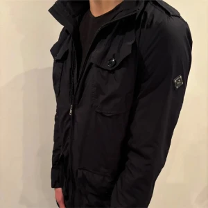 J Lindeberg field jacket - Hej! Säljer nu denna sjukt snygga och sällsynt marinblå jacka från J Lindeberg. Modellen: Bailey. Ordinarie pris 4000:-, mitt pris 1 500:-. Jackan har en liten defekt men som går att lösa väldigt smidigt. Perfekt nu till våren och svalare sommarkvällar. Hör av dig vid minsta fundering! OBS, passar även till L