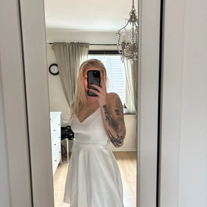 Studentklänning strl 36 - Vacker vit klänning perfekt för festliga tillfällen! Klänningen har en söt, feminin design med spetsdetaljer i ryggen och ett vackert fall.  Den är perfekt för konfirmation, skolavslutning eller andra speciella evenemang, själv hade jag den på min student! Klänningen är alltså bara använd 1 gång och är i toppen skick och redo att bäras.