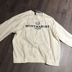 Vit sweatshirt med Montmartre Paris-tryck - Säljer en stilren vit sweatshirt