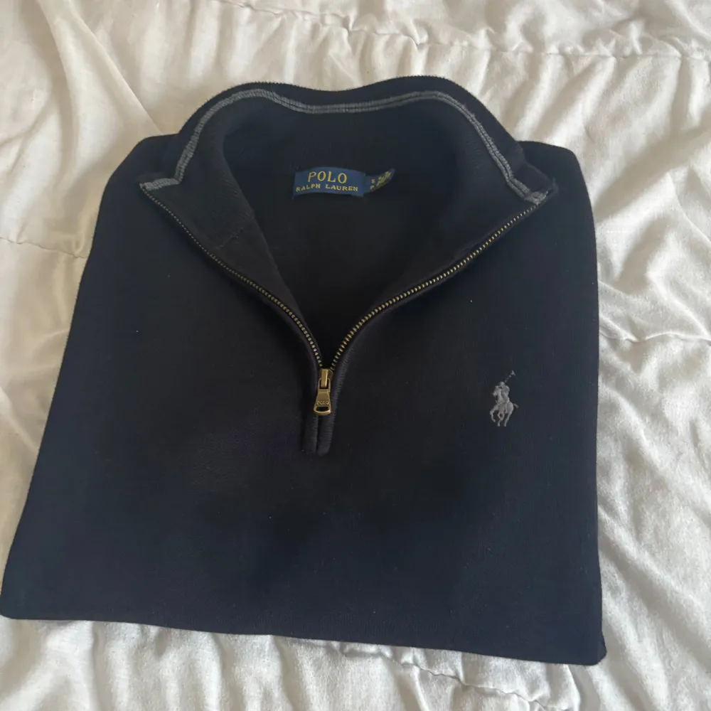 Säljer en stilren svart tröja från Polo Ralph Lauren. Den har en halv dragkedja och det klassiska logotypbroderiet på bröstet. Perfekt för både vardag och lite finare tillfällen. Tröjan är i bra skick och kommer med originalförpackning.. Hoodies.