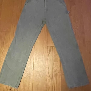 Carhartt dubble knee - Säljer ett par oliv gröna carhartt byxor baggy\loose väldigt bra skick 10/10, priset kan diskuteras vid snabb affär, saknar knapp vid gylfen därför lägre pris.