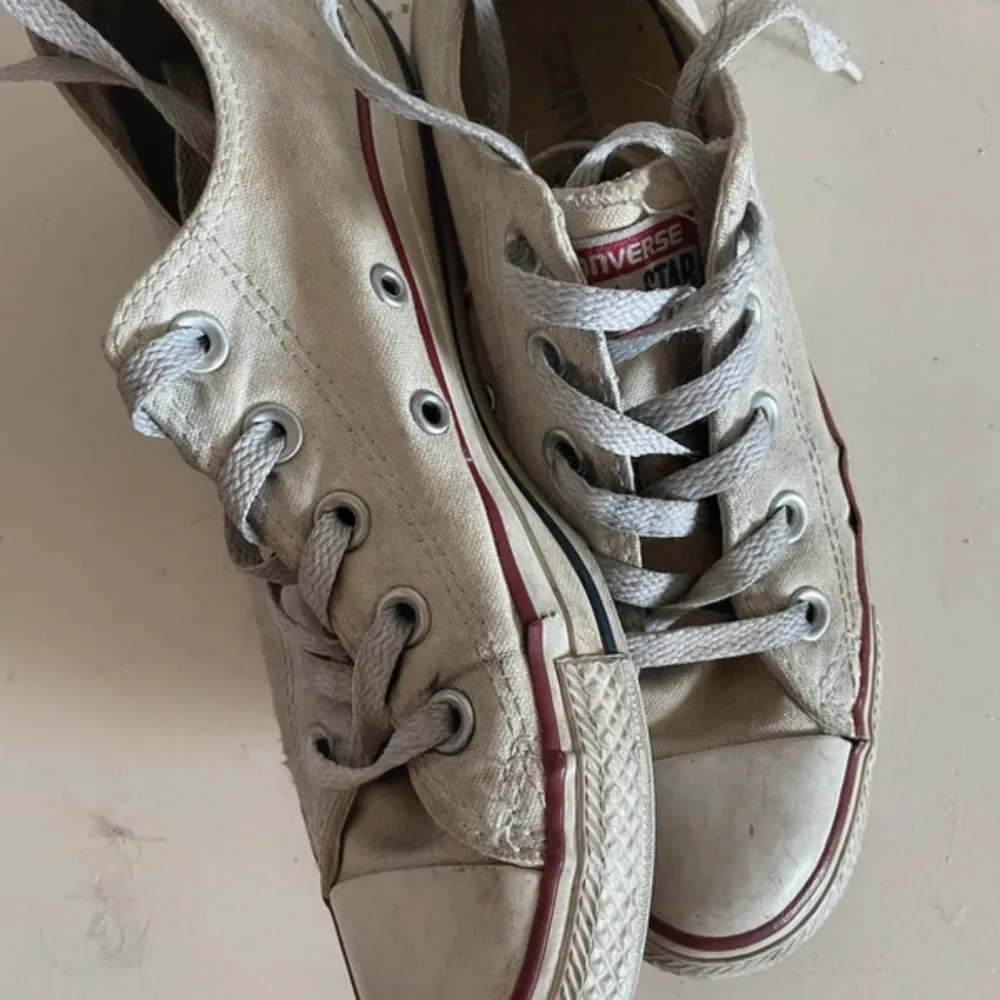 Säljer ett par vita Converse All Star sneakers i välanvänt skick. De har klassisk snörning och den ikoniska röda och blå randen runt sulan. Perfekta för en avslappnad stil, men de har sett bättre dagar och behöver lite kärlek. Men en tvätt så är de nog vita och fräscha igen. Skor.