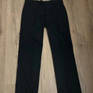 Svarta kostymbyxor  - Svarta herr kombyxor i nyskick. Passar till bröllop, fest, finare tillställningar men även till vardags. Inga anmärkningar.