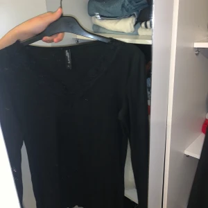 Svart ribbad tröja från Jean Pascale - Säljer en stilren svart ribbad tröja från Jean Pascale i storlek S. Den har en vacker spetsdetalj vid den v-ringade halsen och långa ärmar. Perfekt för både vardag och fest! 🖤