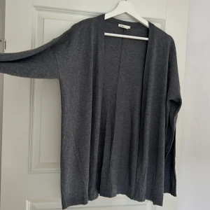 Grå stickad cardigan - Mellangrå finstickad cardigan från HM, ganska tunn. Strl S Pris 40kr