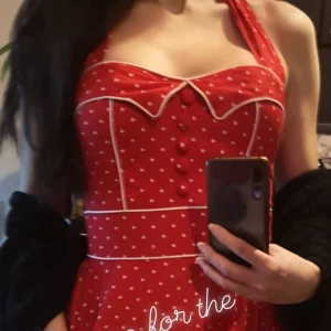 Hell Bunny Vixen Polkadot Klänning, halterneck  - Supersöt klänning halterneck, i Rockabilly-stil. strl S. Klänningen har 2 riktiga fickor fram och 5 dekorationsknappar samt vita sömmar som verkligen framhäver bysten. Smock baktill och dragkedja. Endast använd vid 1 tillfälle.