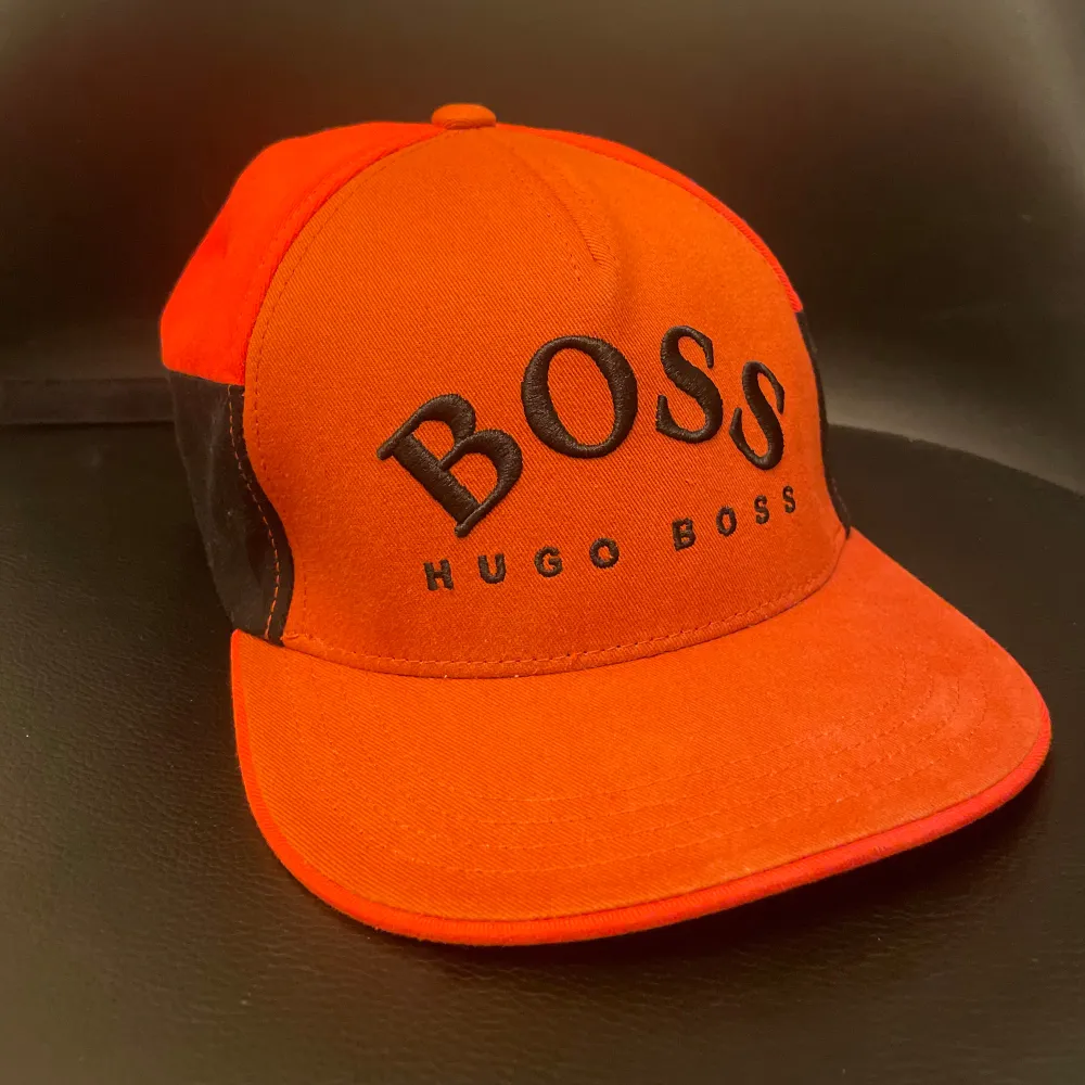 Säljer en snygg orange keps från Hugo Boss med svart broderad logga framtill. Använt den 2-3 gånger, efter det har den legat i garderoben i snart 2 år.. Accessoarer.