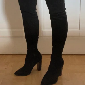 Overknee stövlar i svart faux mocka - Stövlar i svart mockaimitation från Bianco. Endast använda en kväll så i fint skick förutom en skada på insidan av klacken (se sista bilden)