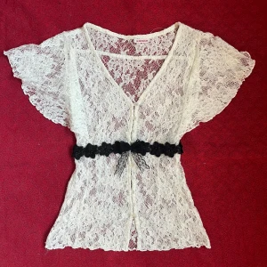 Spetsblus med blomband och rosett - Sjukt söt topp/blus med knappar och såå coola ärmar och ett band av svarta blommor under brösten med en svart rosett i mitten. I mycket fint skick utan skador. Köpt vintage. Perfekt för hösten. Skriv privat om ni har frågor🖤
