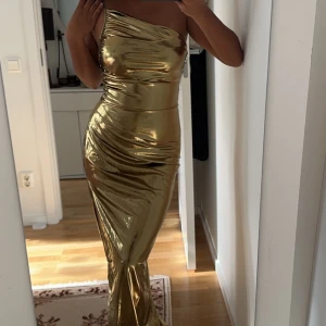 Klänning guld - Har aldrig använt denna klänningen köpte den för en utklädnad på halloween. Jätte vacker fest klänning som skiner och med slits på ena sidan av benet. Sitter så fint speciellt vid midjan. Priset kan även förhandlas!