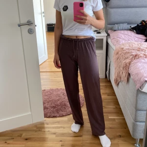 Bruna mjukisbyxor - Säljer ett par bruna mjukisbyxor som är superbekväma och perfekta för en chill dag hemma. De har en elastisk midja med snörning för bästa passform. Materialet känns mjukt och skönt mot huden.