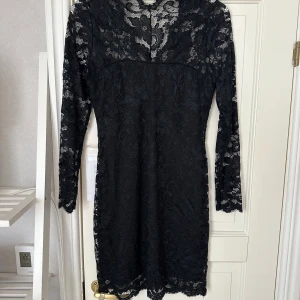 Spetsklänning - Svart spetsklänning med mönster i spetsen där den övre delen endast är spets i storlek M / 38 från Model Behaviour med V-ringning. Endast använd vid ett tillfälle, i gott skick.