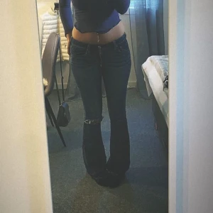 Lågmidjade bootcut jeans  - Säljer nu dessa lågmidjade bootcut jeans med ett hål i ena knät. Säljer då det tyvär blivit för små. Köpta på plick tidigare och är i mycket fint skick. Midjemått 40 rakt över innerbenslängd 82.