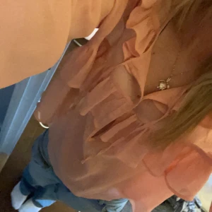 Persikofärgad blus med volanger - Säljer en söt persikofärgad blus med volanger. Den är inköpt iår och är inprincip oanvänd. Passar xs-s