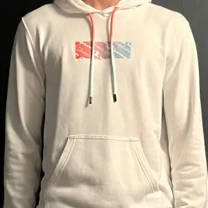 En vit hoodie från Champion med tryck på bröstet. Den har storleken M och är en lite tunnare hoodie. Väldigt bra skick.