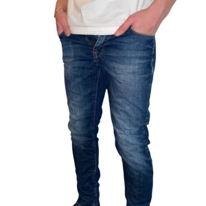 J.Lindeberg jeans - Snygga blå jeansbyxor med en slim passform och klassisk femficksdesign. De har en dragkedja och knapp framtill. Perfekta för en stilren look.