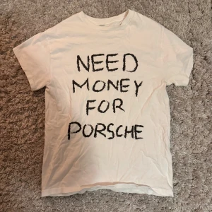 Need money for porsche t-shirt - Säljer en vit t-shirt med texten 'NEED MONEY FOR PORSCHE' i svart. Perfekt för den som vill ha ett roligt inslag i garderoben. Kortärmad och i en klassisk passform.