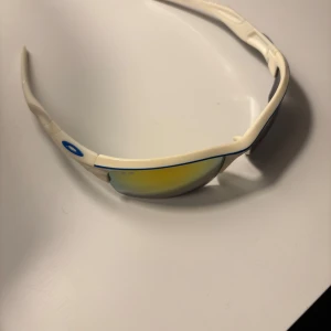 Vita sportiga solglasögon från oakley - Snygga vita solglasögon från oakley. Skick 10/10. Använda fåtal gånger. De har en smidig passform och är lätta att bära. Skriv för fler frågor😁