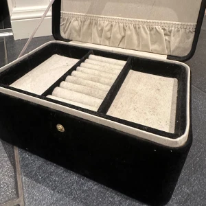 Svart smyckeskrin  - Elegant svart smyckeskrin med flera fack för organisering av smycken. Insidan är klädd i mjukt material för att skydda dina smycken. Perfekt för att hålla ordning på ringar, armband och halsband. Vet inte vart den är ifrån men super fin förutom lite luddig som förmodligen går att ta bort!🥰🥰