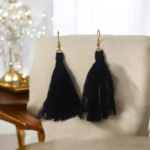 Svarta tofsörhängen - Snygga svarta örhängen med långa tofsar som ger en trendig look. Perfekta för att lägga till en touch av stil till din outfit. De har guldfärgade krokar för enkel användning.