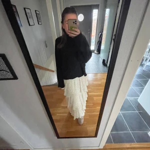 Vit prickig kjol med volanger Gina tricot  - Säljer en superfin vit långkjol med små svarta prickar och flera lager av volanger. Kjolen har en luftig och romantisk stil, perfekt för att ge en bohemisk touch till din outfit. Den är elastisk i midjan för en bekväm passform.