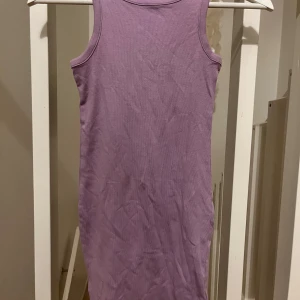 Lila ribbad klänning - Säljer en söt lila ribbad klänning i ärmlös design. Perfekt för varma dagar med sin enkla och stilrena look. Passar utmärkt för både lek och avslappnade tillfällen. 💜