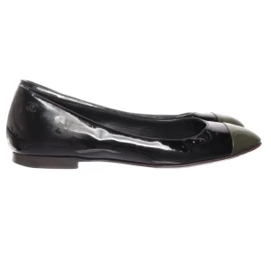 Svarta ballerinaskor från Chanel - Eleganta svarta ballerinaskor från Chanel med en glansig finish och rund tå. Skorna har en subtil logotypdetalj på sidan och är tillverkade i Italien. Perfekta för en stilren look.