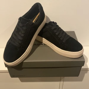 Svarta sneakers från Vagabond - Snygga svarta sneakers från Vagabond i mocka med vit sula. Skorna har klassisk snörning och en stilren design som passar perfekt till vardagsoutfiten. Stor i storleken så passar även 42-43. Ny pris 1400. Pris 1000